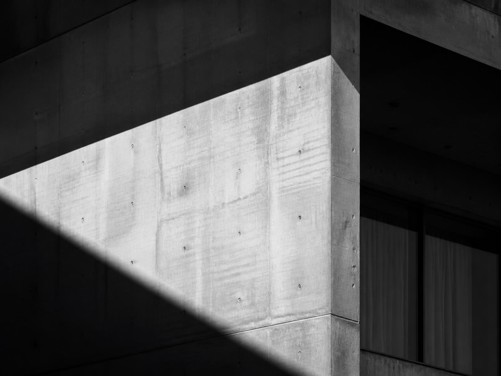 High-contrast architectural facade cut by a diagonal shaft of light
