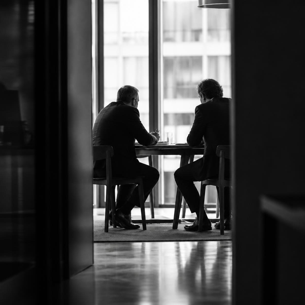 Two executives in a candid strategy discussion beside a window